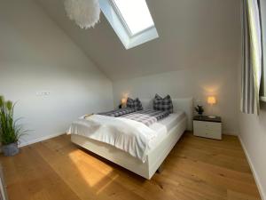 a white bedroom with a bed and a skylight at Reeders Topp by Seeblick Ferien in Olpenitz