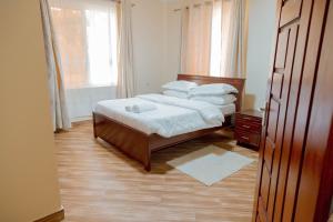 a bedroom with a bed with white sheets and a window at Rhovee Homes in Moshi