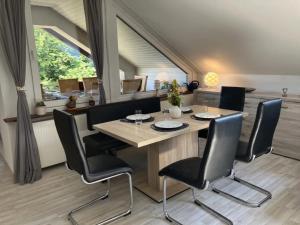 a dining room with a wooden table and black chairs at Ferienwohnung Sauerlandherz in Lennestadt