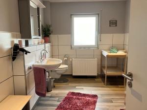 a bathroom with a sink and a toilet and a window at Ferienwohnung Sauerlandherz in Lennestadt +23 photos