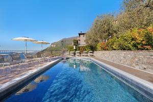a swimming pool with chairs and an umbrella at Rustico Spagnol 1 in Tignale