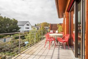 a patio with red chairs and a table on a balcony at Seekind in Kressbronn am Bodensee