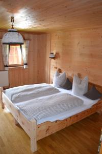 a large bed in a room with a wooden wall at Ferienhaus Obersäuling in Stummerberg