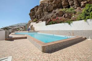 a swimming pool in front of a wall with a mountain at Casa Boti in Puerto Rico de Gran Canaria