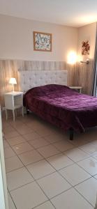a bedroom with a large bed with a purple comforter at Domaine de Meslay in Fyé