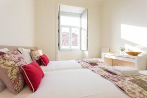 ein weißes Schlafzimmer mit einem großen weißen Bett mit roten Kissen in der Unterkunft FLH Baixa Modern Place in Lissabon