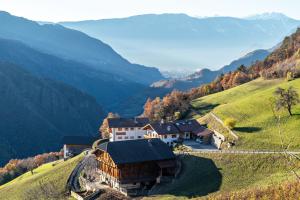 a house on a hill with mountains in the background at Guntschöllerhof Hochwart in Völs am Schlern
