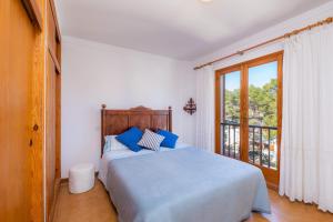 a bedroom with a bed with blue pillows and a window at Mastil in Cala Millor