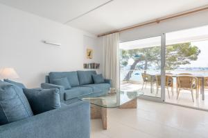 a living room with a blue couch and a glass table at Catalina 2a tres dormitorios in Port de Pollensa