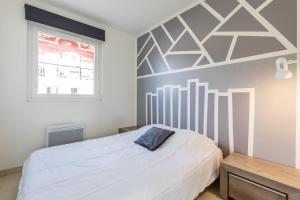 a bedroom with a white bed with a geometric wall at Chalet Climatisé Biscarrosse in Parentis-en-Born +16 photos