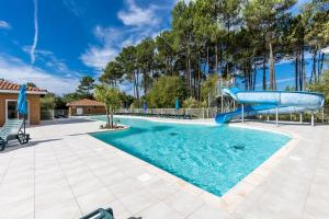 a swimming pool with a slide in a yard at Chalet Climatisé Biscarrosse in Parentis-en-Born