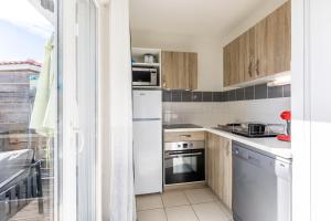 a kitchen with white appliances and wooden cabinets at Chalet Climatisé Biscarrosse in Parentis-en-Born