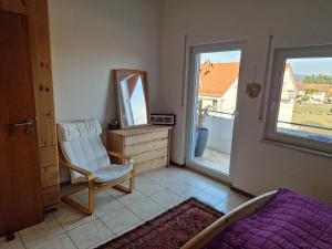 a bedroom with a chair and a mirror and a window at Ferienwohnung Storchenblick in Raisting
