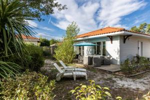 a white house with a bench in the yard at Chalet Climatisé Biscarrosse in Parentis-en-Born