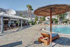 a resort with a pool and an umbrella and chairs at Evripides family one -bedroom 1 in Kardamaina