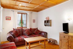 a living room with a red couch and a table at Zum Schnitzer Franzl in Garmisch-Partenkirchen