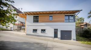 a white house with a wooden roof on a street at Wohnplatz 52 in Inzigkofen