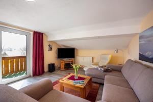 a living room with a couch and a tv at Ferienwohnung Bamberger Gipfelblick in Hopferau