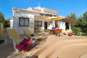 a patio with chairs and a table and an umbrella at Casa da Alfarrobeira in Loulé
