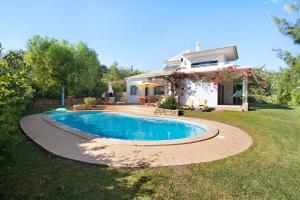 a swimming pool in front of a house at Casa da Alfarrobeira in Loulé