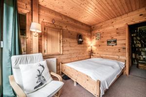 a bedroom with a bed and a chair in a room at La Rissole - Chalet familial in Châtel