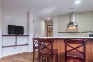 a kitchen with a bar with two chairs and a tv at Valle del Ibias - Primero Izquierda in Cecos
