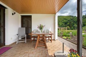 a patio with a wooden roof and a table with flowers at Abendrot in Münsingen