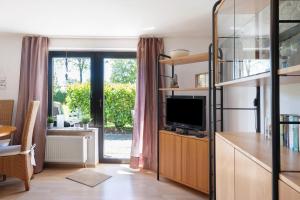 a living room with a tv and a sliding glass door at An der Silberfuchsbörse in Wurster Nordseeküste