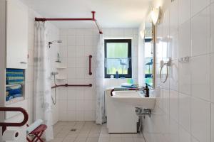 a white bathroom with a sink and a shower at An der Silberfuchsbörse in Wurster Nordseeküste +20 photos