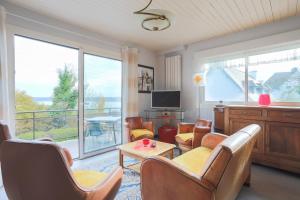 a living room with a couch and chairs and a television at Bellevue rue de la petite corniche in Perros-Guirec