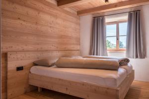 a bed in a room with wooden walls and a window at Egger an der Lahn - Apt Dolomiten in San Genesio Atesino