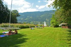 a group of people sitting on the grass in a park at Villa Müller Turmfalke in Ossiach