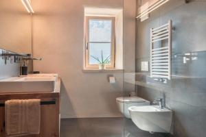 a bathroom with a toilet and a sink and a window at Egger an der Lahn - Apt Dolomiten in San Genesio Atesino