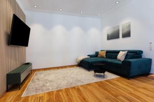 a living room with a blue couch and a flat screen tv at Breisgau Lofts - Nähe Europapark in Herbolzheim