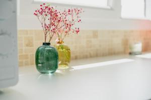 two vases sitting on a counter with flowers in them at Logement calme proche centre ville in Rennes +13 photos