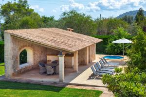 a pavilion with a table and chairs and a pool at Can noble den suau in Pollença
