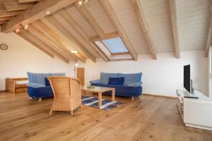 a living room with blue couches and a tv at Ferienwohnung Schleinseeblick in Kressbronn am Bodensee
