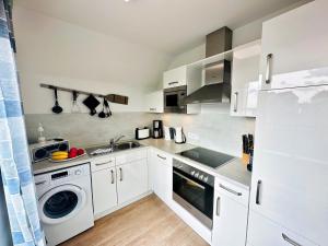 a kitchen with white cabinets and a washer and dryer at Räuberhöhle by Seeblick ferien oro in Kappeln