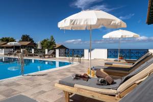 a pool with two lounge chairs and an umbrella at Sunset Triple 2 in Lefkada