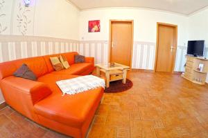 a living room with an orange couch and a table at Ferienbauernhof - Ferienwohnung 5 in Grünow