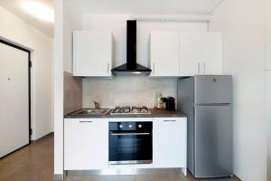 a kitchen with white cabinets and a stainless steel refrigerator at Appartamento 5 Il Tornante in Nesso