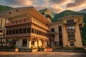 a large building with mountains in the background at Norbu Lingka Resort in Tongsa