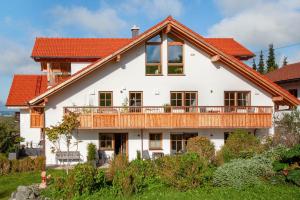 a large white house with a deck at Allpano Pension und Ferienwohnungen in Dietmannsried