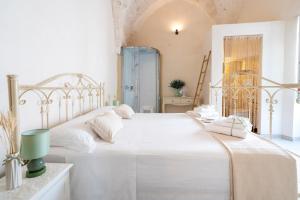 a white bedroom with a large bed with white sheets at Suite Cavour 30 in Ostuni