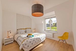 a bedroom with a bed and a yellow chair at À la maison de Goulannou in Tréflez