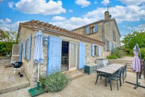 a stone house with blue doors and a table and chairs at La Maison Roudier in Razac-dʼEymet