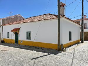a white building with a green door on a street at Retiro Do Tejo in Malpica