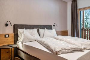 a bedroom with a large bed with white sheets at Kamerloy Apartments B in Campitello di Fassa
