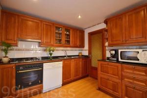 a kitchen with wooden cabinets and a black and white appliance at Benestar in El Toro +7 photos