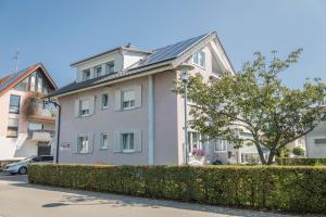 a white house with a hedge in front of it at Ferienwohnung Lilo in Immenstaad am Bodensee